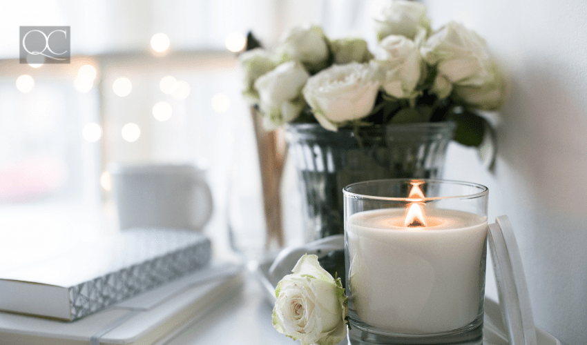 white candle burning in front of potted white roses