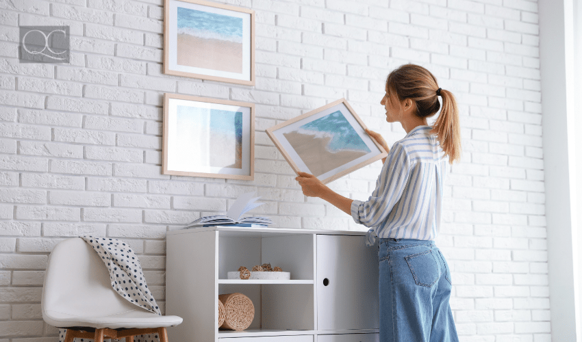 design course article, in-post image, woman hanging up artwork on wall at home