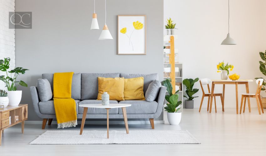 Orange blanket on grey sofa in modern apartment interior with poster and wooden table.