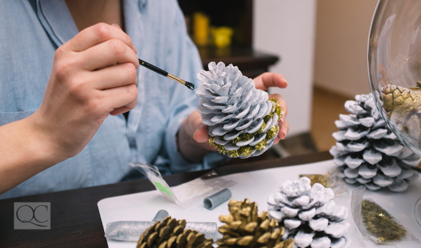 woman painting a pine cone to DIY decorate