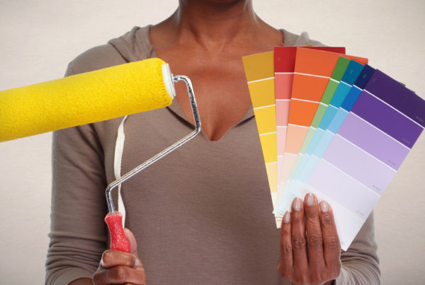 professional color consultant holding up paint swatches and a roller brush with wall paint color