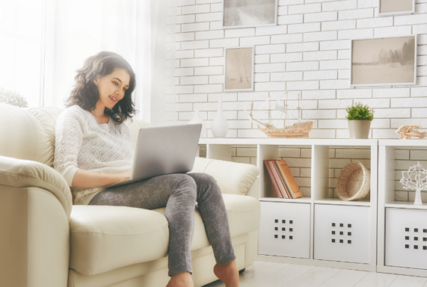 Woman sitting on couch reading QC Design School blog article on laptop