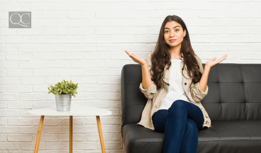 woman sitting on cough and shrugging