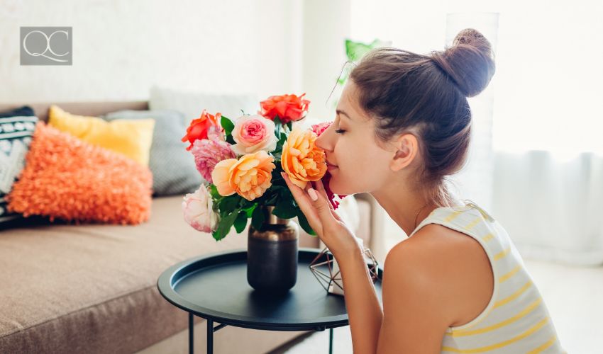 Interior decorating course article, July 22 2021, in-post image, woman happily smelling flowers in vase on living room coffee table