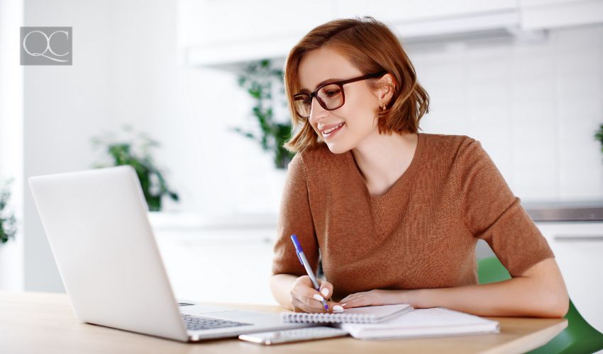 Woman on remote work or online education, using laptop computer, making notes, indoors at office or home at daytime. Online business, young professional at workplace. Working from home.