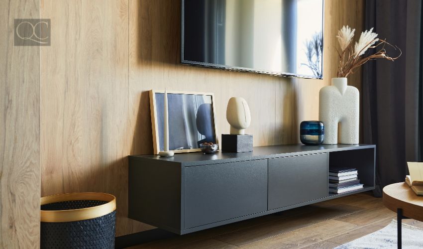 Creative composition of details of modern living room interior in small apartment Black commode, creative vase, books, tv and personal accessories.