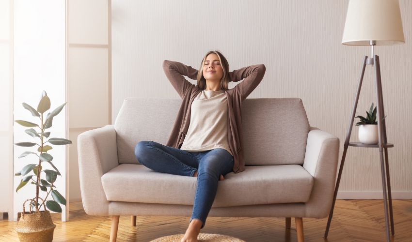 Finally weekends. Millennial girl relaxing at home on couch, enjoying free time, empty space. Interior design mental health article.